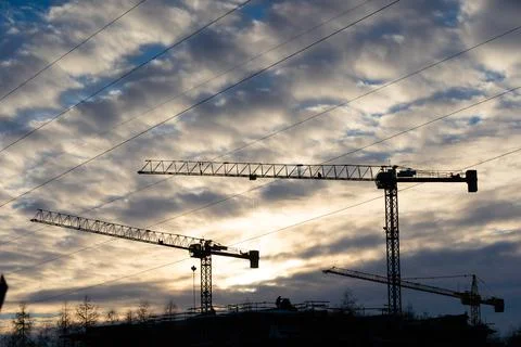A tall construction crane against the setting sun. Machine for high-altitude Stock-Fotos