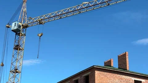 A tall construction crane extends over a partially visible brick building Stock Footage 310628265