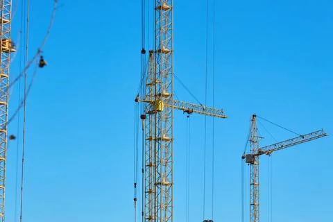 A tall construction crane is seen working under a clear blue sky Stock Photos