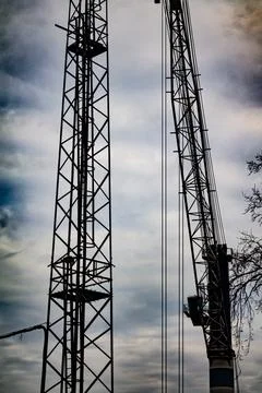 Tall construction cranes against cloudy sky Foto stock
