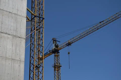 A tall construction tower crane against a blue sky. Stock Photos