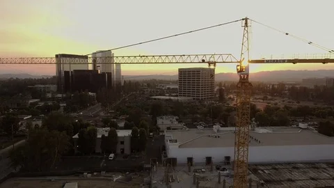 Tall crane with sun behind modern skyline Stock-Footage 77631490