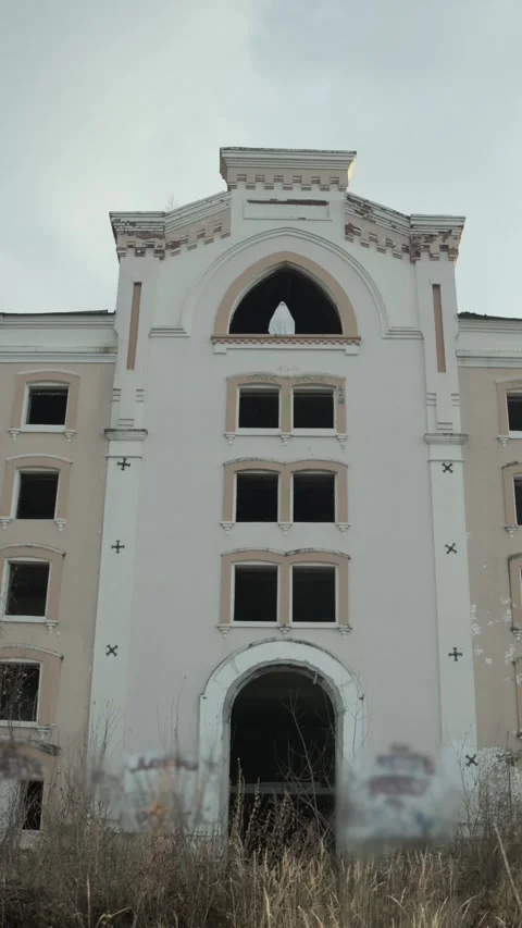 Tall derelict structure, high arched window dominates facade, ghost resembling Stock Footage 320248734