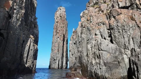 Tall dolerite sea stack beside towering cliffs on the Tasman Peninsula Stock Footage 347276673