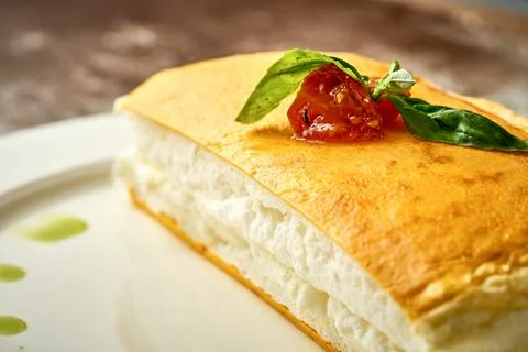 A tall egg omelet with lettuce on a white plate. Selective focus. Noise in po Stock Photos