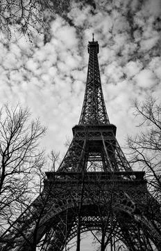 Tall Eiffel Tower rising into cloudy Paris sky, black and white vertical photo Foto stock