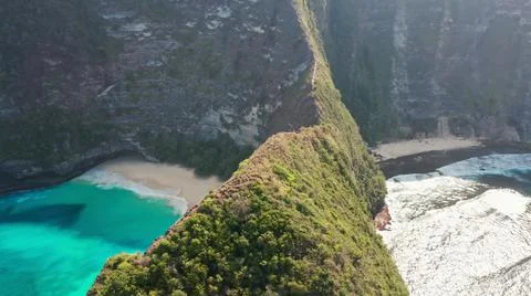 The tall elephant cliffs blocking the waves are covered with green trees and  Stock Photos