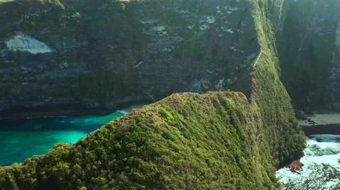 The tall elephant cliffs blocking the waves are covered with green trees and  Foto stock
