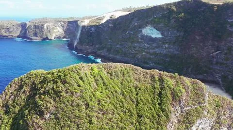 The tall elephant cliffs blocking the waves are covered with green trees and  Stock Photos