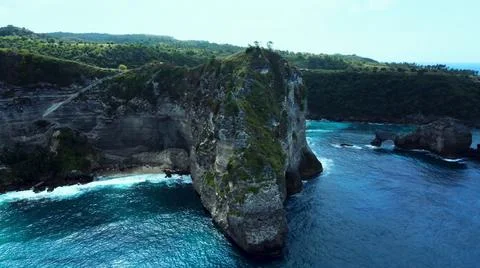 The tall elephant cliffs blocking the waves are covered with green trees and  Stock Photos