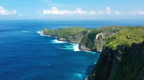The tall elephant cliffs blocking the waves are covered with green trees and  Stock Photos