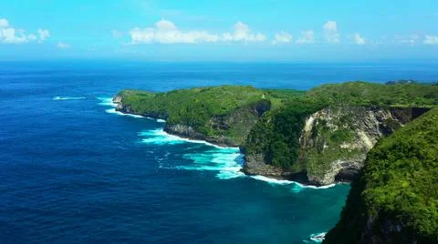 The tall elephant cliffs blocking the waves are covered with green trees and  Foto stock