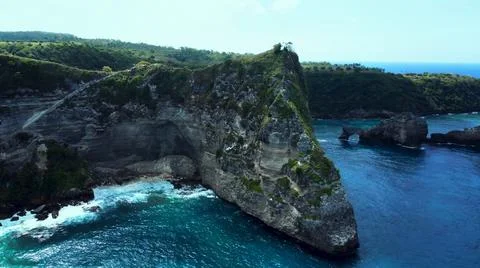 The tall elephant cliffs blocking the waves are covered with green trees and  Stock Photos