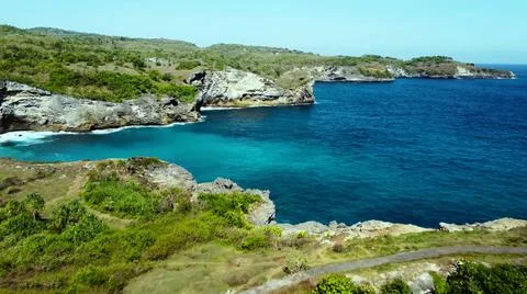 The tall elephant cliffs blocking the waves are covered with green trees and  Stock Photos