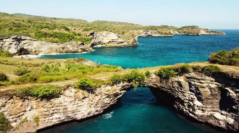 The tall elephant cliffs blocking the waves are covered with green trees and  Stock Photos