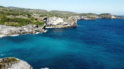 The tall elephant cliffs blocking the waves are covered with green trees and  Stock Photos