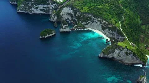 The tall elephant cliffs blocking the waves are covered with green trees and  Stock Photos