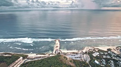 The tall elephant cliffs blocking the waves are covered with green trees and  Stock Photos