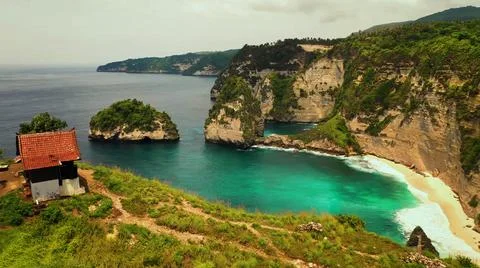 The tall elephant cliffs blocking the waves are covered with green trees and  Stock Photos
