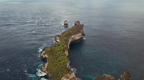 The tall elephant cliffs blocking the waves are covered with green trees and  Stock Photos