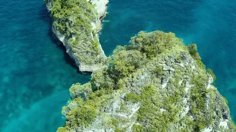 The tall elephant cliffs blocking the waves are covered with green trees and  Foto stock