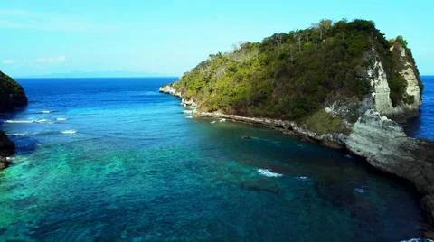 The tall elephant cliffs blocking the waves are covered with green trees and  Stock Photos