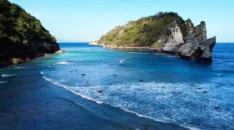 The tall elephant cliffs blocking the waves are covered with green trees and  Stock Photos