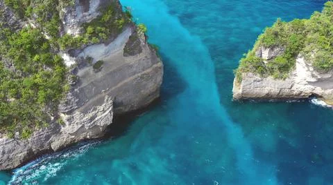 The tall elephant cliffs blocking the waves are covered with green trees and  Stock Photos