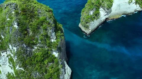 The tall elephant cliffs blocking the waves are covered with green trees and  Stock Photos