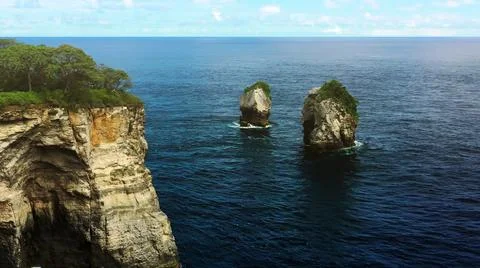 The tall elephant cliffs blocking the waves are covered with green trees and  Stock Photos
