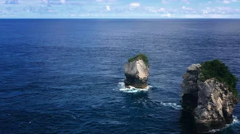 The tall elephant cliffs blocking the waves are covered with green trees and  Stock Photos
