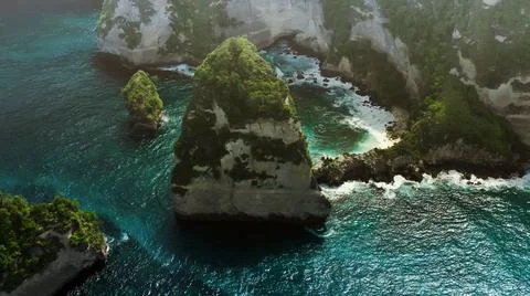 The tall elephant cliffs blocking the waves are covered with green trees and  Foto stock