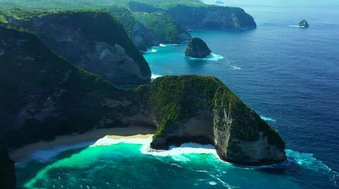The tall elephant cliffs blocking the waves are covered with green trees and  Stock Photos