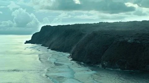 The tall elephant cliffs blocking the waves are covered with green trees and  Foto stock