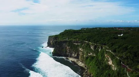 The tall elephant cliffs blocking the waves are covered with green trees and  Foto stock