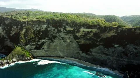 The tall elephant cliffs blocking the waves are covered with green trees and  Stock Photos