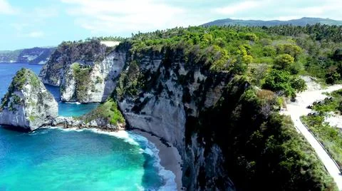 The tall elephant cliffs blocking the waves are covered with green trees and  Stock Photos