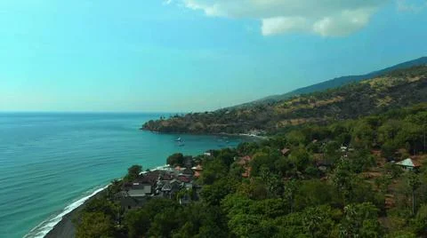 The tall elephant cliffs blocking the waves are covered with green trees and  Stock Photos