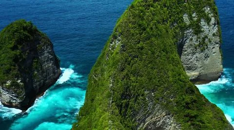 The tall elephant cliffs blocking the waves are covered with green trees and  Stock Photos