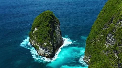The tall elephant cliffs blocking the waves are covered with green trees and  Stock-Fotos