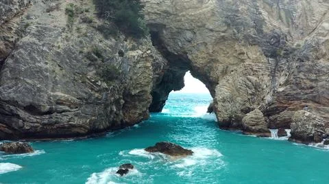 The tall elephant cliffs blocking the waves are covered with green trees and  Stock Photos