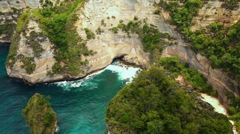 The tall elephant cliffs blocking the waves are covered with green trees and  Foto stock