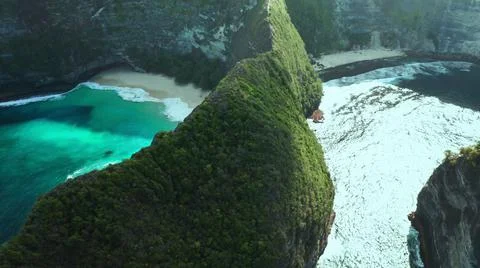 The tall elephant cliffs blocking the waves are covered with green trees and  Stock Photos