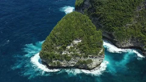 The tall elephant cliffs blocking the waves are covered with green trees and  Stock Photos