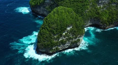 The tall elephant cliffs blocking the waves are covered with green trees and  Stock Photos