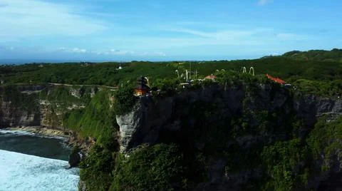 The tall elephant cliffs blocking the waves are covered with green trees and  Stock Photos