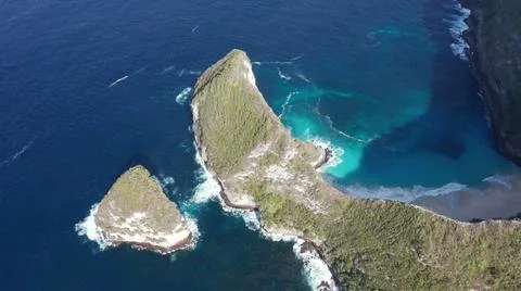 The tall elephant cliffs blocking the waves are covered with green trees and  Stock Photos