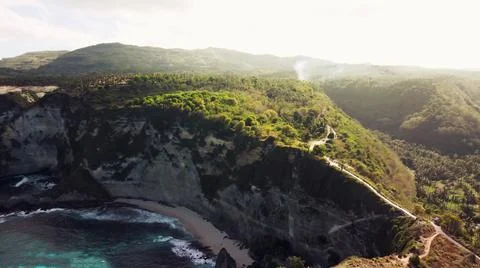 The tall elephant cliffs blocking the waves are covered with green trees and  Stock Photos