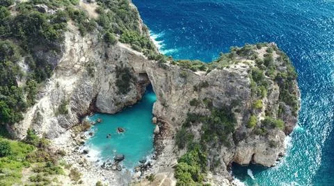 The tall elephant cliffs blocking the waves are covered with green trees and  Stock Photos