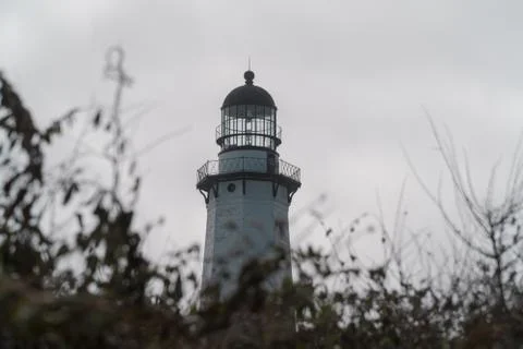 Tall generic lighthouse peer over green nature space shrubs and trees Stock Photos